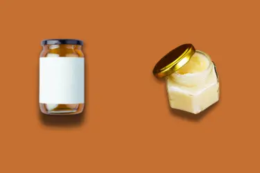 A liquid honey jar next to a creamed honey jar against a dark orange background